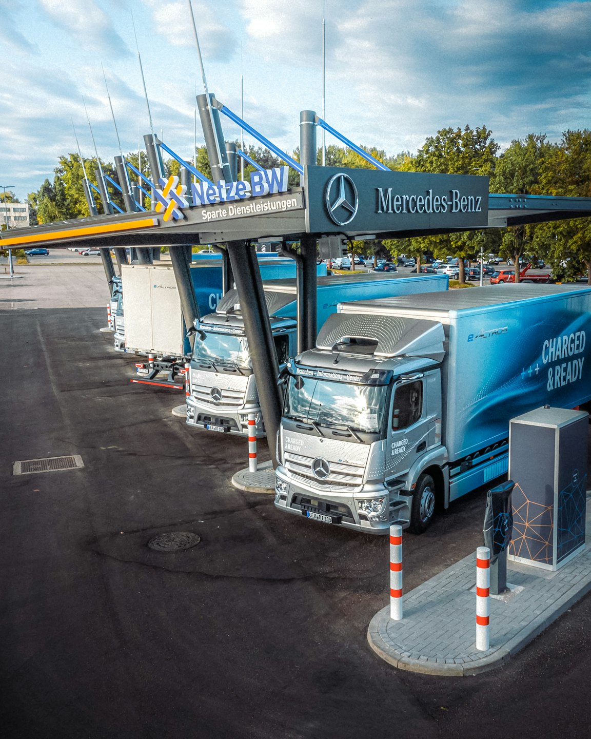 Modern electric semi-trucks charging at a depot.